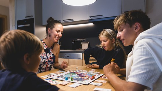 Familie sitzt gemeinsam am Tisch und spielt ein Brettspiel Familie sitzt gemeinsam am Tisch und spielt ein Brettspiel