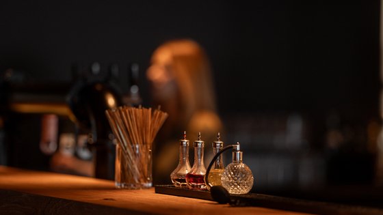 Bar-Equipment steht auf der Bar verschwommen im Hintergrund steht eine Barkeeperin Bar-Equipment steht auf der Bar verschwommen im Hintergrund steht eine Barkeeperin
