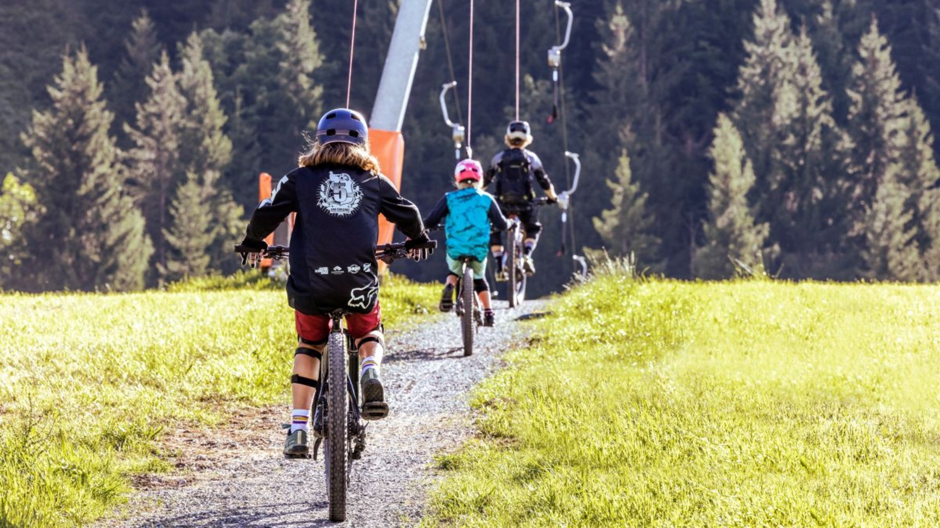 Kinder auf Fahrrädern am Schlepplift in der Bike Area Fieberbrunn Kinder auf Fahrrädern am Schlepplift in der Bike Area Fieberbrunn