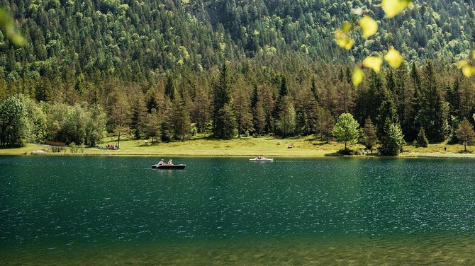Wandern in Fieberbrunn – einfach herrlich! Bergsee mit Ruderbooten vor bewaldeten Bergen und blauem Himmel