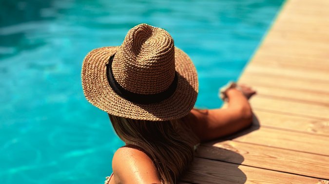 Frau mit Sonnenhut entspannt im glasklaren Schwimmteich Frau mit Sonnenhut entspannt im glasklaren Schwimmteich