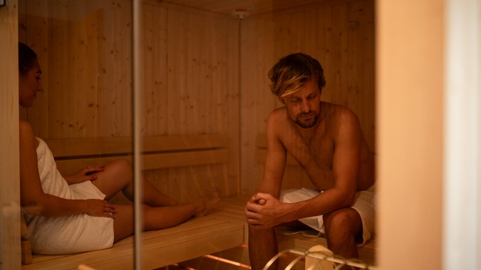 Urlaub für... Mann und Frau entspannen in einer Holzsauna mit Handtüchern