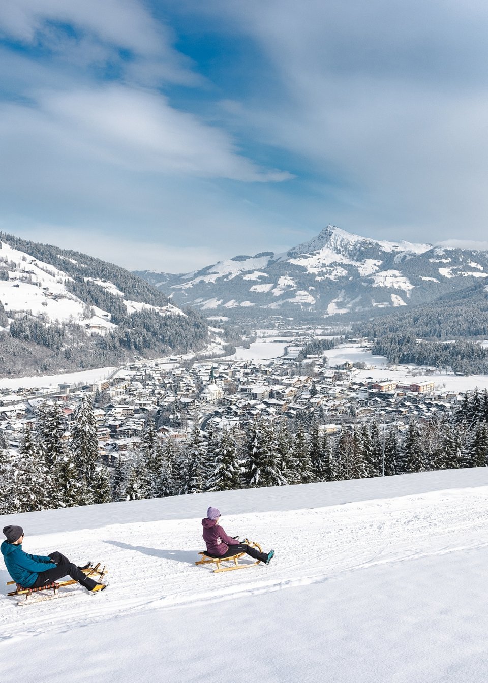 Zwei Freunde rodeln den verschneiten Berg hinab in Tirol Zwei Freunde rodeln den verschneiten Berg hinab in Tirol