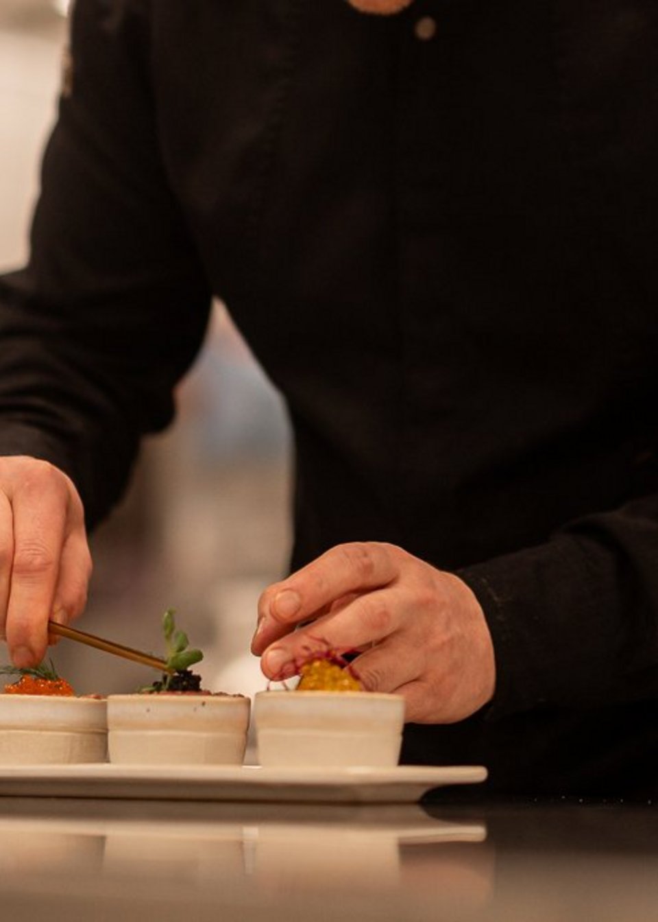 Koch richtet liebevoll die Speisen an im UPSIDEDOWN Koch richtet liebevoll die Speisen an im UPSIDEDOWN