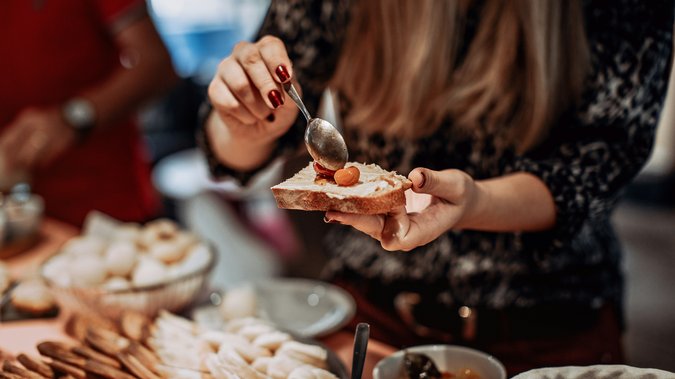 Hochzeitslocation in Tirol: ADEA Lifestyle Suites Frau bestreicht ein Brot mit Creme und legt eine Olive darauf