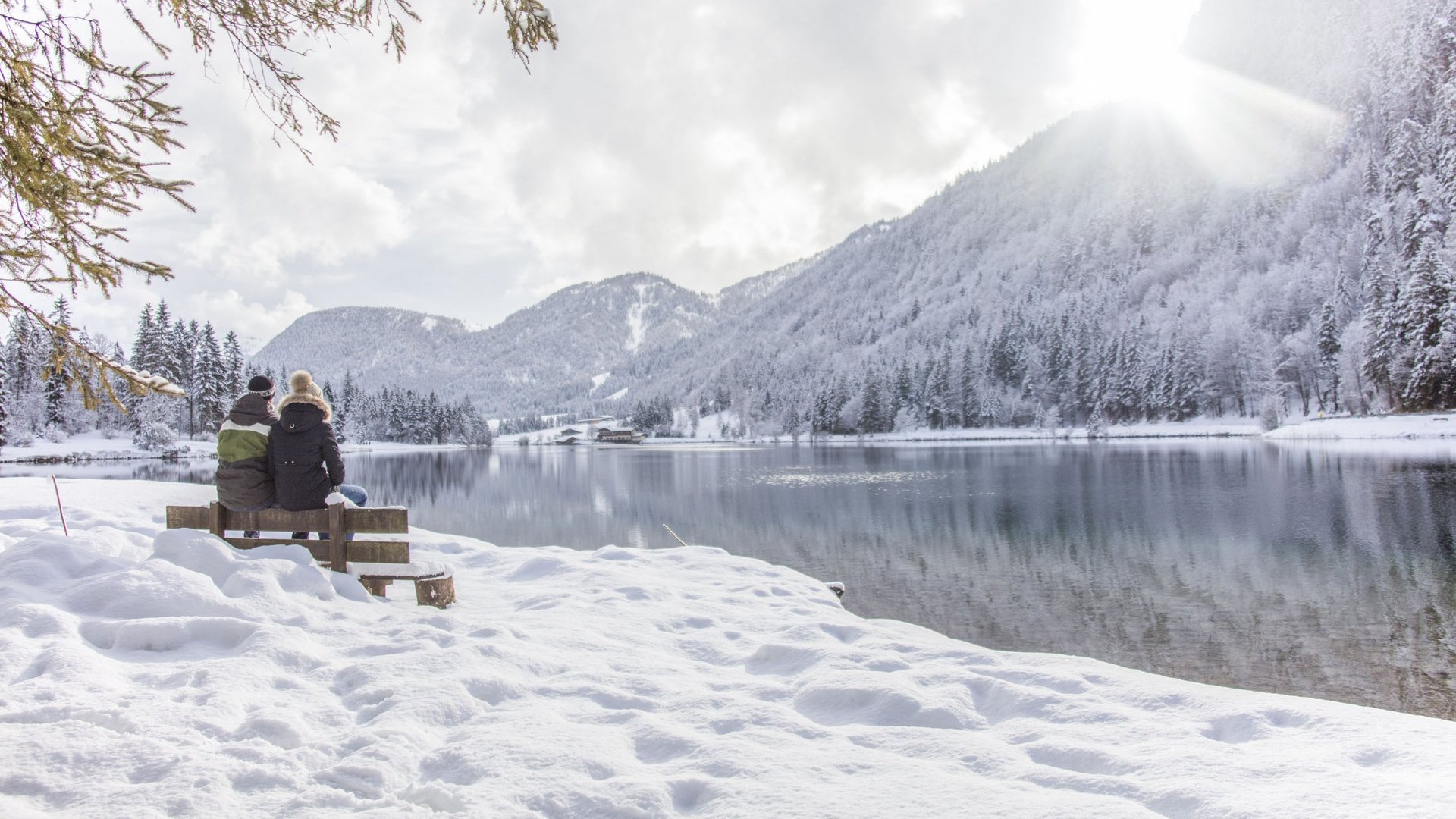 Paar sitzt auf Bank und genießt die Aussicht auf die winterliche Landschaft Paar sitzt auf Bank und genießt die Aussicht auf die winterliche Landschaft