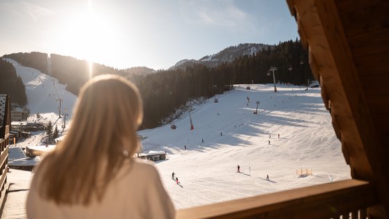 Frau blickt vom Balkon auf die Skipiste Frau blickt vom Balkon auf die Skipiste