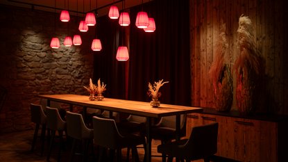 langer Esstisch mit Hochstühlen und roten Lampen in der Lobby Lounge in Fieberbrunn langer Esstisch mit Hochstühlen und roten Lampen in der Lobby Lounge in Fieberbrunn