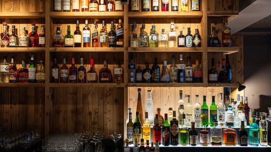 Holzregal mit einer Auswahl an Spirituosen hinter der Bar Holzregal mit einer Auswahl an Spirituosen hinter der Bar