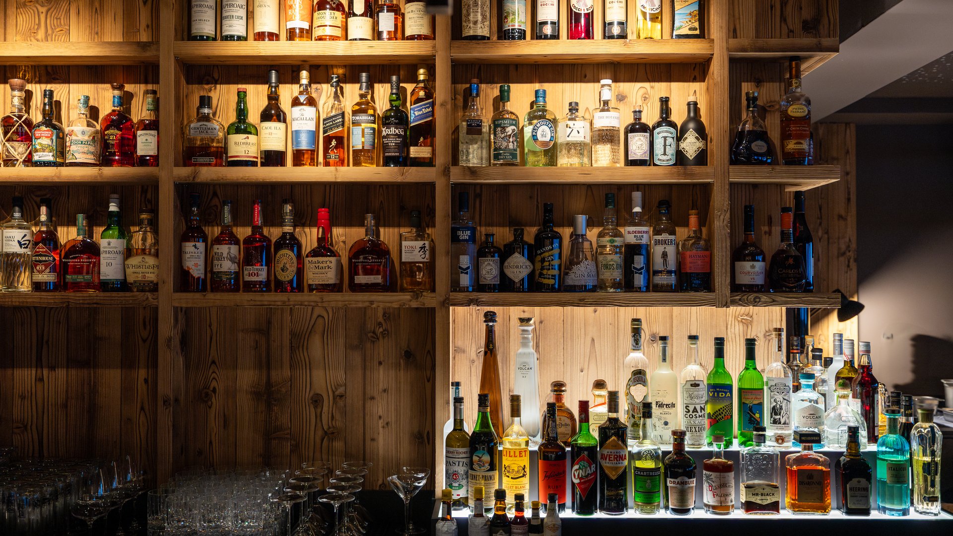 Spirituosen Auswahl hinter der Bar in einem Holzregal Spirituosen Auswahl hinter der Bar in einem Holzregal