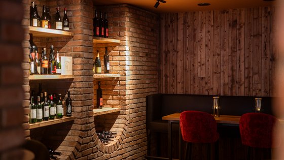 Weinlounge mit Sitzmöglichkeit und einem voll gefülltem Weinregal Weinlounge mit Sitzmöglichkeit und einem voll gefülltem Weinregal