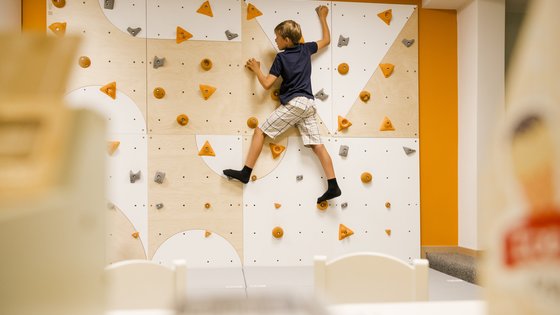 Kind klettert auf einer Kletterwand im Kinderspielzimmer Kind klettert auf einer Kletterwand im Kinderspielzimmer