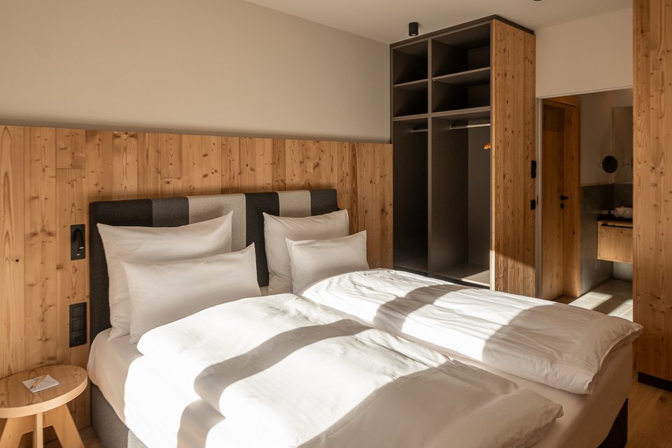 ADEA: dein Hotel mit Fitnessstudio in Österreich Modernes Schlafzimmer mit Doppelbett, Holzwänden und offenem Kleiderschrank