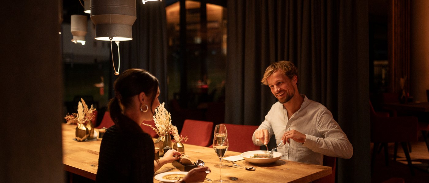 UPSIDEDOWN Restaurant Paar sitzt glücklich beim Abendessen im Restaurant UPSIDEDOWN in Fieberbrunn