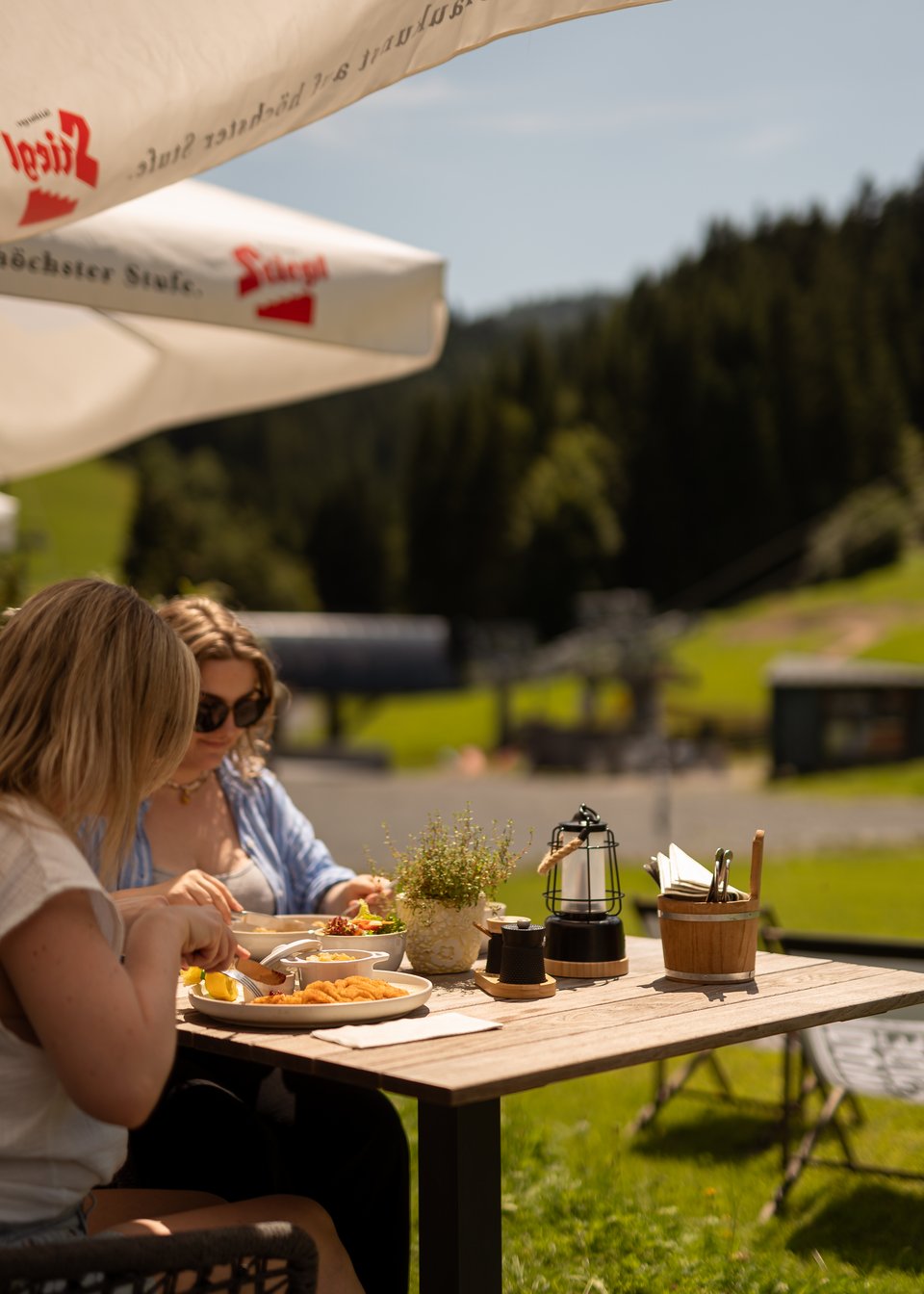 Hotel in Fieberbrunn: ADEA Lifestyle Suites 2 Frauen sitzen auf der Sonnenterasse und genießen das Essen