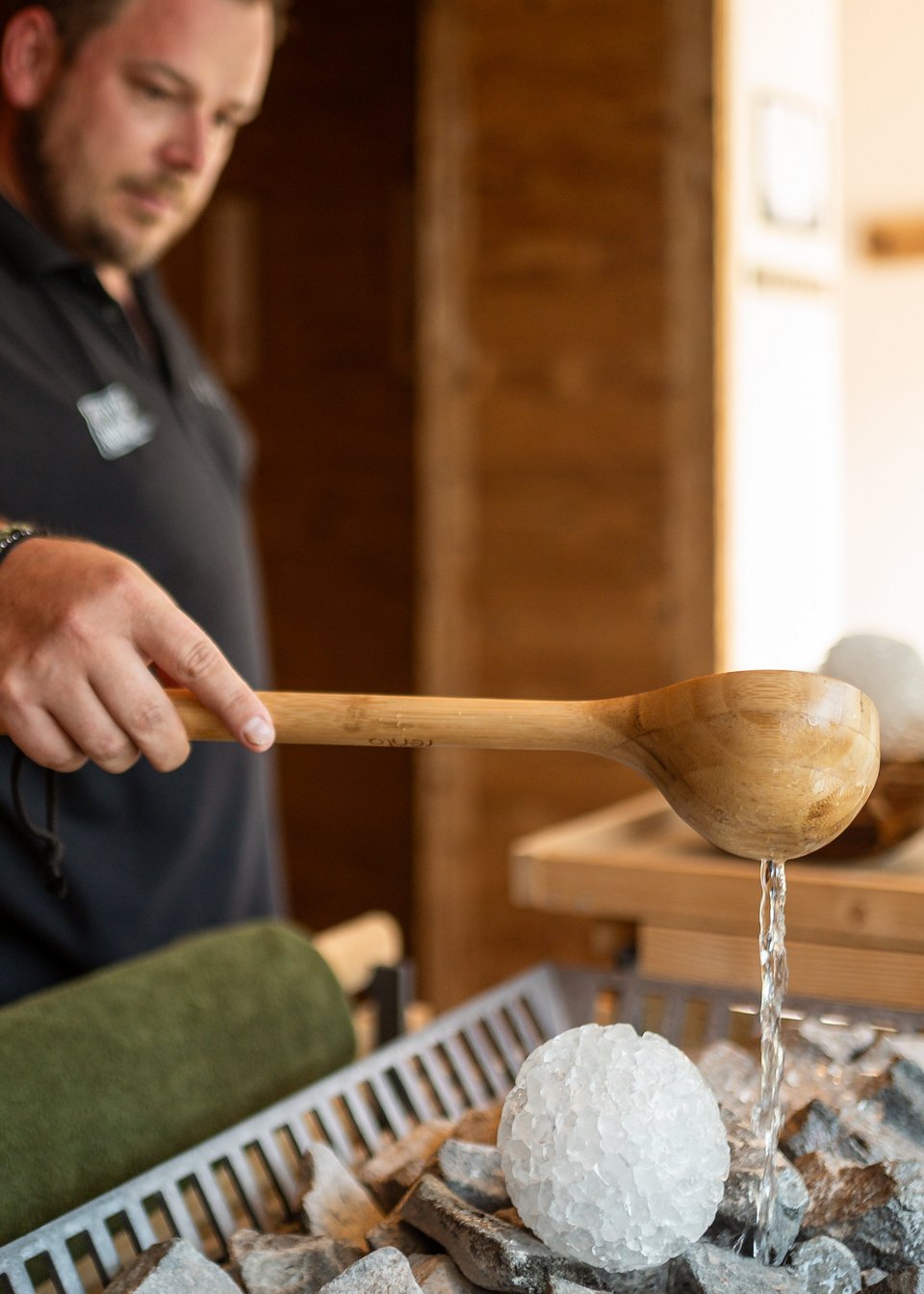 Saunameister steht in der Sauna und macht einen Aufguss Saunameister steht in der Sauna und macht einen Aufguss