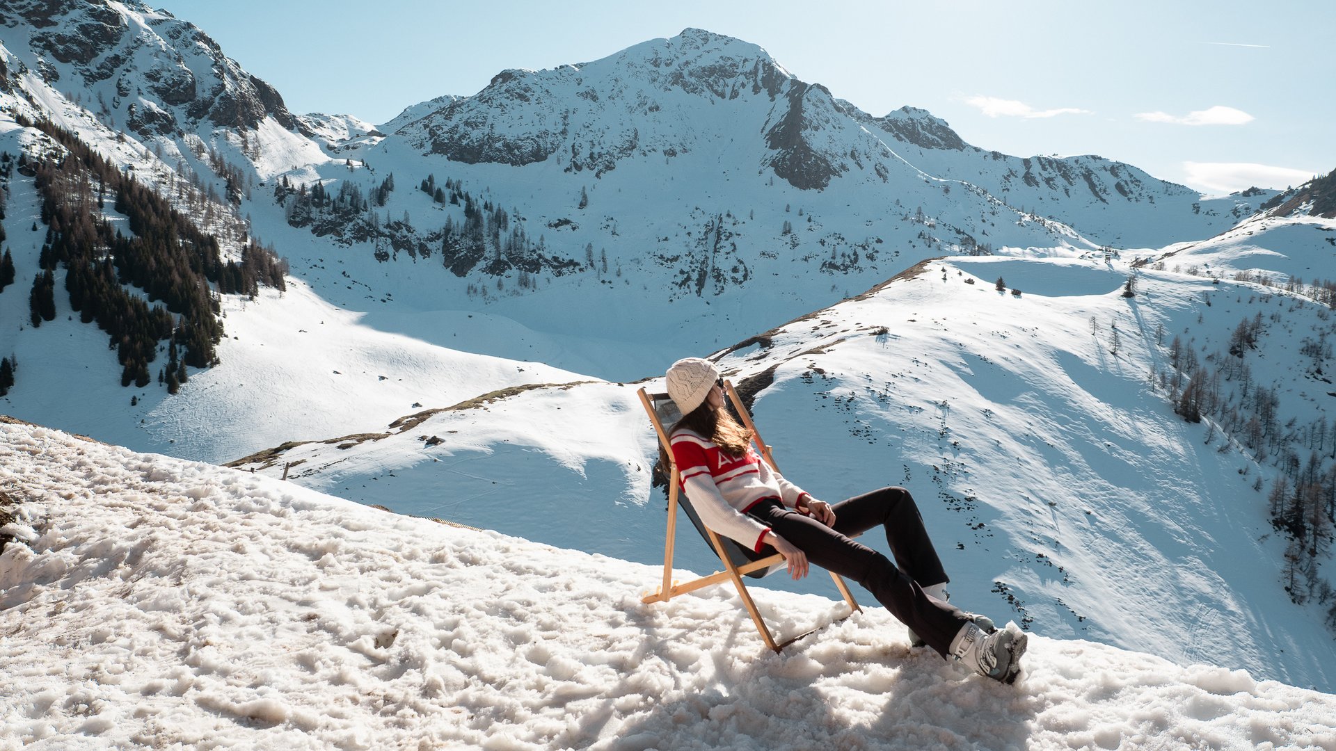 Hotel in Fieberbrunn: ADEA Lifestyle Suites Frau entspannt auf Liegestuhl im Schnee vor schneebedeckten Bergen