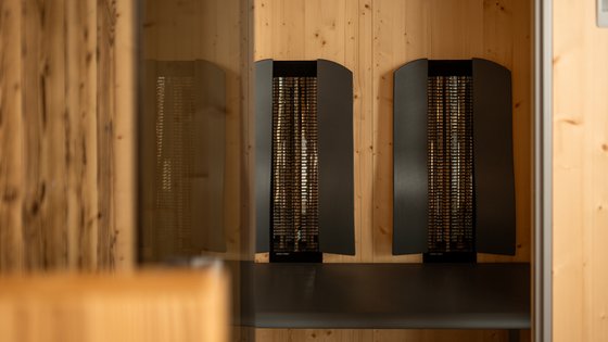 Fieberbrunn: Wellnesshotel gesucht? Schwarzer Infrarot-Heizstrahler an Holzwand in modernem Raum