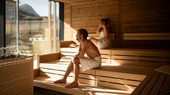 Paar sitzt in Panoramasauna mit Bergblick Paar sitzt in Panoramasauna mit Bergblick
